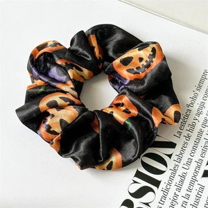 Close-up of black satin scrunchie with orange Halloween pumpkin prints on magazine