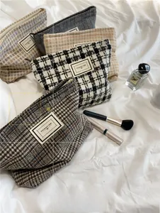 Detailed view of plaid cosmetic bags with metal zippers on a white soft fabric background