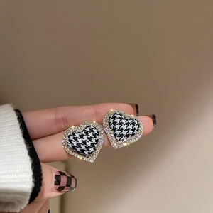Close-up of heart-shaped houndstooth earrings with sparkling rhinestone borders