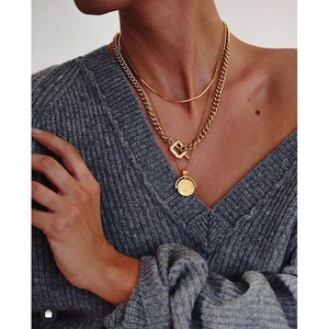 Minimalist gold snake chain and layered coin pendant necklace on a knitted sweater model