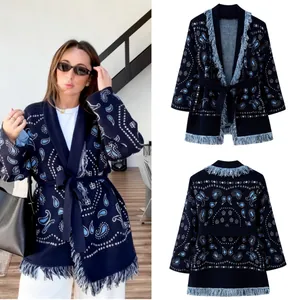 Detail of navy knit cardigan featuring white paisley patterns and elegant blue fringe trim