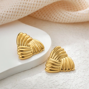Macro shot of gold triangular earrings featuring a unique wavy texture on white stone