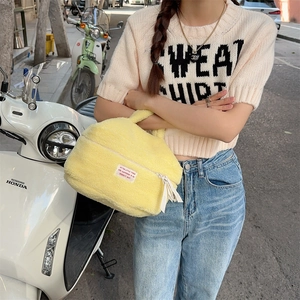 Close-up of bright yellow plush cosmetic bag with soft faux fur texture and zipper detail