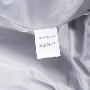 Close-up of internal wash care label on gray jacket showing 100% polyester material