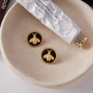 Macro détaillée des boucles d'oreilles abeille en acier doré 18K et émail noir