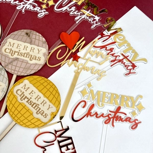 Flat lay of multiple acrylic Merry Christmas cake toppers in gold and silver finishes