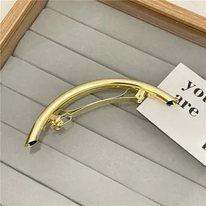 Detailed side view of a minimalist golden tube hair clip on a jewelry display tray