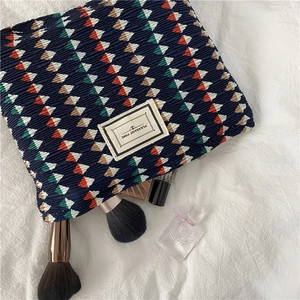 Detail of navy blue pleated chiffon makeup bag with geometric pattern and zipper closure