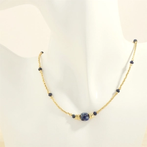 Macro detail of bohemian necklace with blue stone beads and golden metal accents