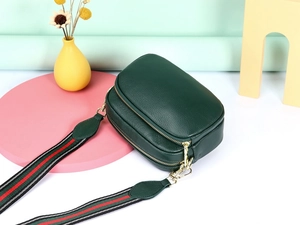 Detail van donkergroene crossbodytas van generfd leer met gestreepte schouderriem