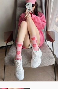 Detail of pink cotton socks featuring red heart patterns and stylish letter embroidery