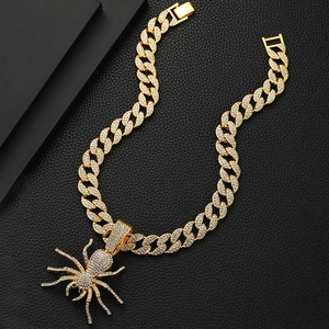 Detailed close-up of golden iced-out Cuban chain with spider pendant on black leather