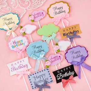 Various Happy Birthday cake toppers with ribbon bows on pink background and lace decor