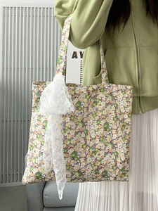 Detailed shot of floral canvas tote bag with purple accents and white lace pendant