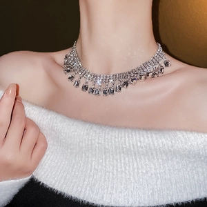Gros plan sur un collier à franges étincelant porté par un mannequin en lumière douce