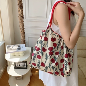 Detailed side view of floral canvas tote bag worn by model in a minimalist room