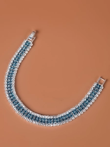 Detail of silver bracelet with sparkling blue and white zircon stones on warm brown background