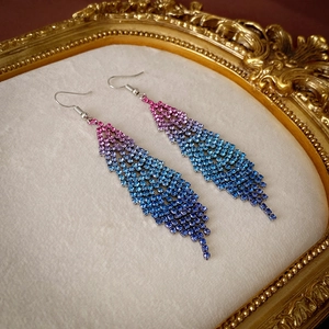 Macro detail of rhinestone tassel earrings with pink to blue gradient in a vintage gold frame