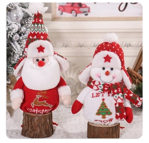 Close-up of knitted Santa and Snowman gift bags with faux fur trim on wooden base