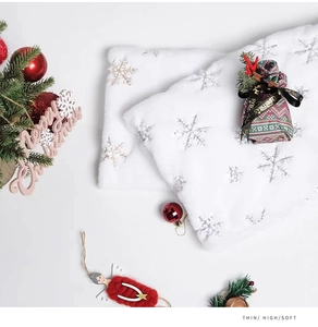 Détail du tissu en peluche blanche avec des flocons de neige argentés pour Noël