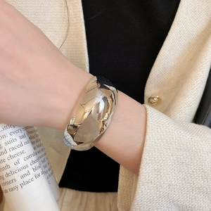 Gros plan sur un large bracelet manchette argenté fluide avec une finition métal poli brillant