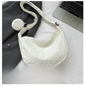 Macro detail of white waffle-textured half-moon bag with removable coin purse attachment