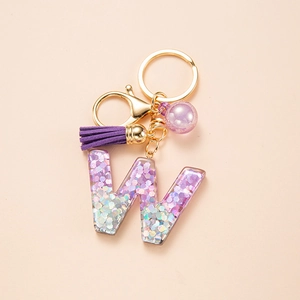 Detail of glitter purple resin letter W keychain with matching tassel and gold hardware