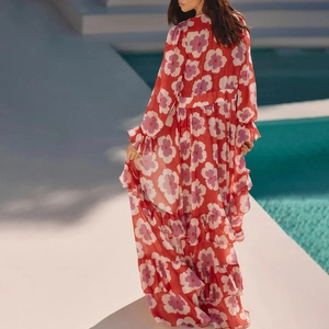 Détail d'une robe maxi rouge à plusieurs couches avec imprimé floral et manches longues