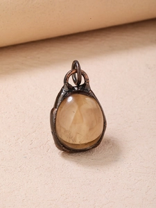 Macro view of a vintage oval translucent brown gemstone set in textured dark metal