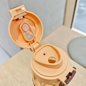 Detailed macro view of orange plastic lid with dual-drinking straw design and seal structure
