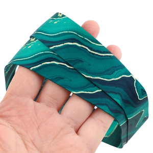 Detail shot of a turquoise marble patterned lanyard held by hand on white background