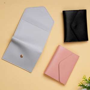 Close-up of envelope style leather card holders in blue, black and pink with snap button