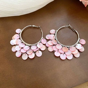 Macro detail of pink shell tassels on large circular hoop earrings for summer vacations