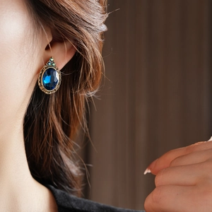 Détail de la boucle d'oreille vintage en pierre bleue ovale avec cadre en métal bronzé