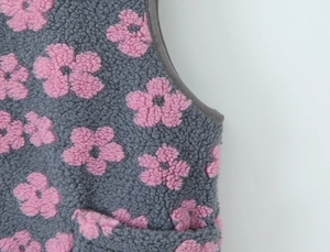 Detail view of thick grey fleece vest with pink floral pattern and premium hem edge