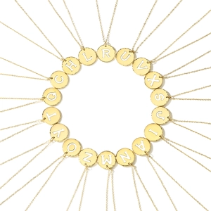 Macro layout of gold-plated necklaces with alphabet enamel round pendants on white base