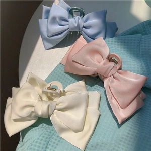 Three large satin bow hair claws in light blue, pink, and cream white for summer hair styling
