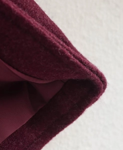 Détail du manteau en laine bordeaux montrant la texture du tissu et la doublure