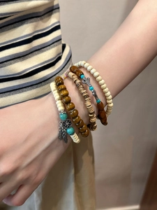 Détail de bracelets bohèmes en bois avec turquoise et breloques vintage portés au poignet