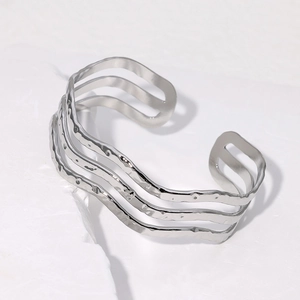 Three-layer wavy open silver stainless steel bracelet on white stone surface