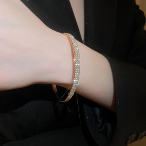Close-up of elegant gold plated bangle with sparkling cubic zirconia on a black suit sleeve