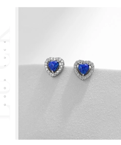 Détail de boucles d'oreilles cœur en opale bleue avec base en argent et pierres brillantes