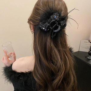 Detail of large black hair claw clip with sequins and fluffy feathers on model's hair