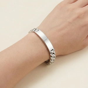 Detailopname van een zilveren roestvrijstalen ID-armband met schakels in horlogebandstijl.