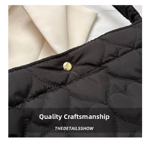 Detail of heart-shaped quilting on black nylon tote bag with golden snap button