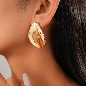 Close-up of high-shine gold water drop earring on model showcasing metallic luster