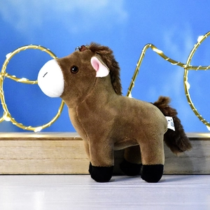 Vue latérale d'un mignon porte-clés en peluche cheval brun sur un support en bois
