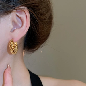 Gros plan sur une boucle d'oreille en C plaquée or 18 carats à texture tressée