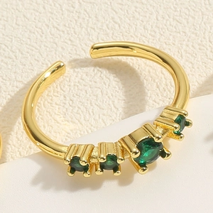 Détail macro d'une bague vague plaquée or 14K avec trois pierres précieuses vertes