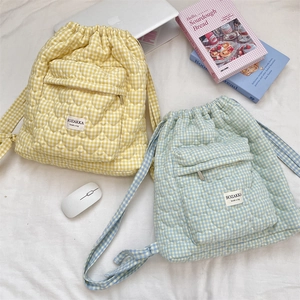 Flat lay of quilted heart pattern drawstring backpacks in yellow and light blue colors